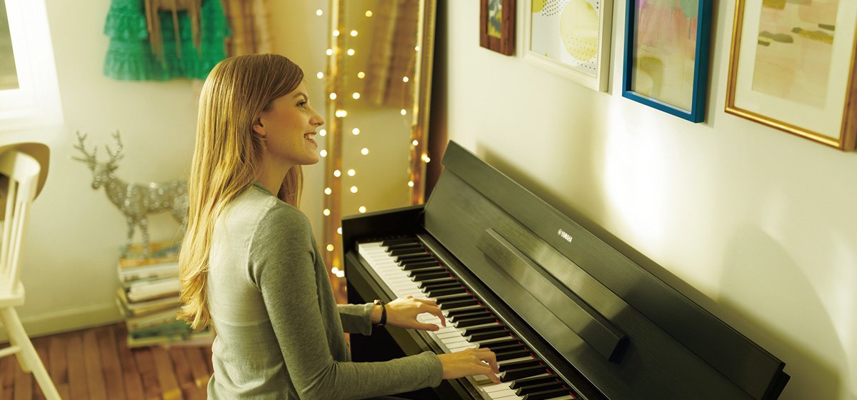 девушка играет на цифровом пианино Yamaha дома